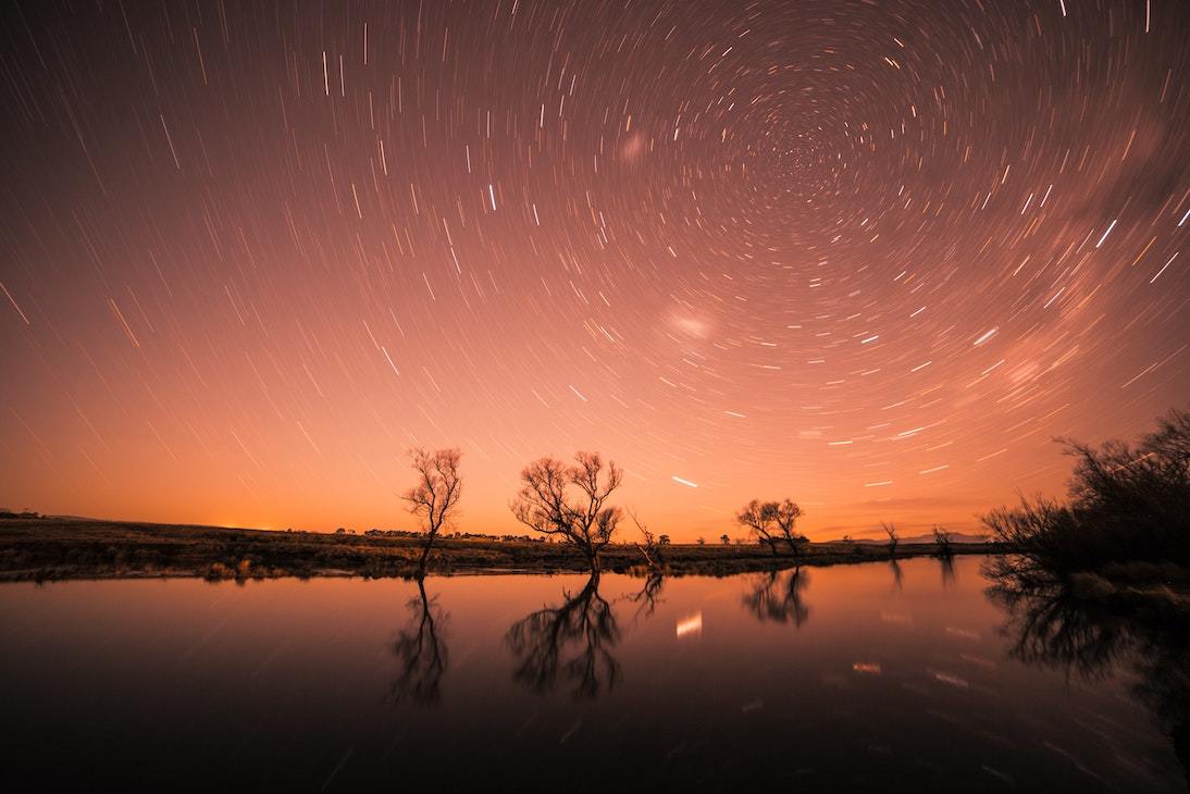 Star swirl in orange sky over water